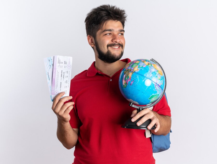 young-bearded-student-guy-red-polo-shirt-with-backpack-holding-air-tickets-globe-looking-aside-with-smile-happy-face-standing-white-wall_141793-101965